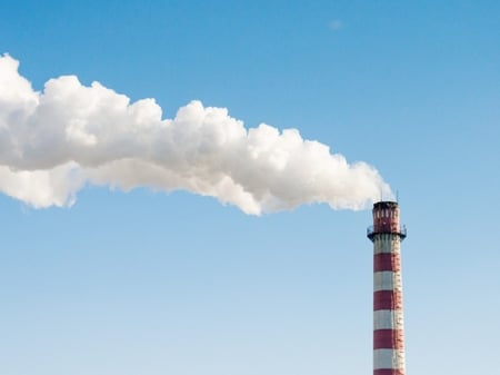 White plume rising from a red and white industrial smokestack