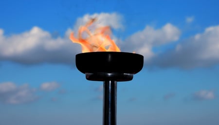 Gas flare burning at the top of a stack against a blue sky