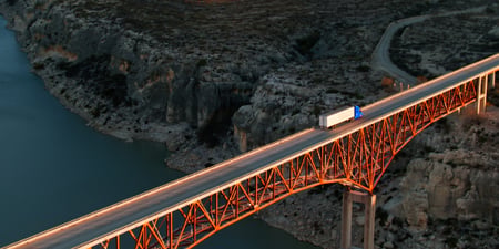 blue truck hauling waste on a bridge