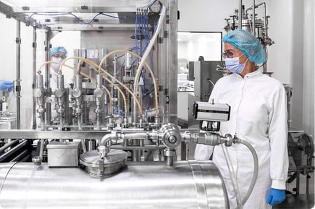 Worker in protective clothing moves chemical waste container