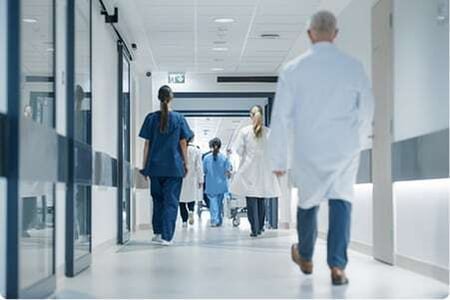 Medical professionals walk down a hospital hallway