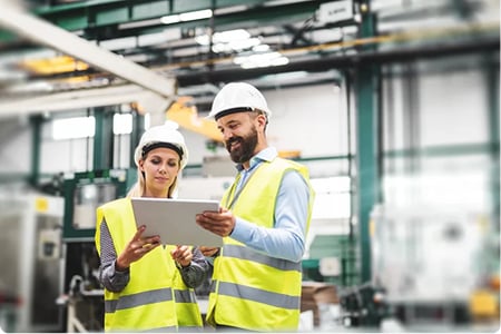 Two team members consult printed plans in a manufacturing environment