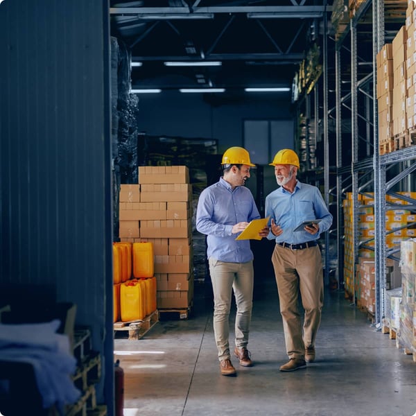 Two men walk in industrial facility discussing waste solutions needs.