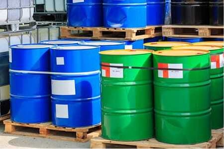 Rows of industrial barrels holding waste materials in a storage area.
