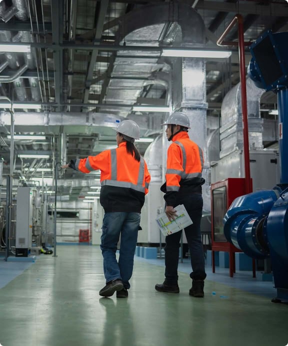 Two workers walk through warehouse for secure disposal review.