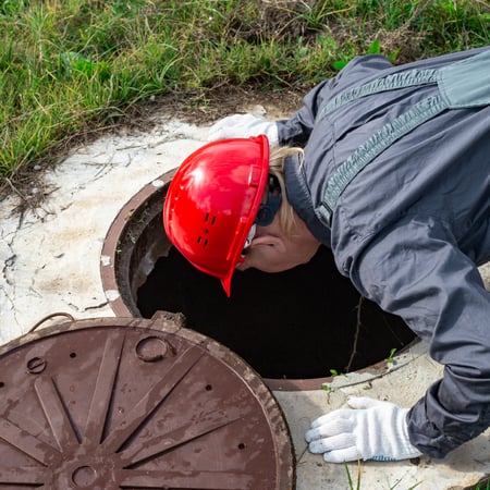 an engineer looking down a manhole