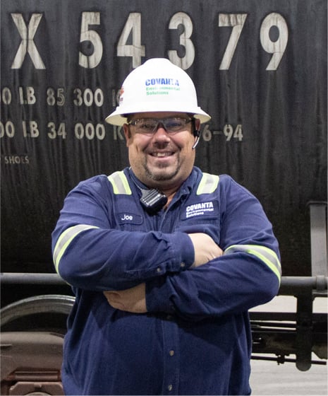 a CES employee smiles with arms crossed in front of a rail car